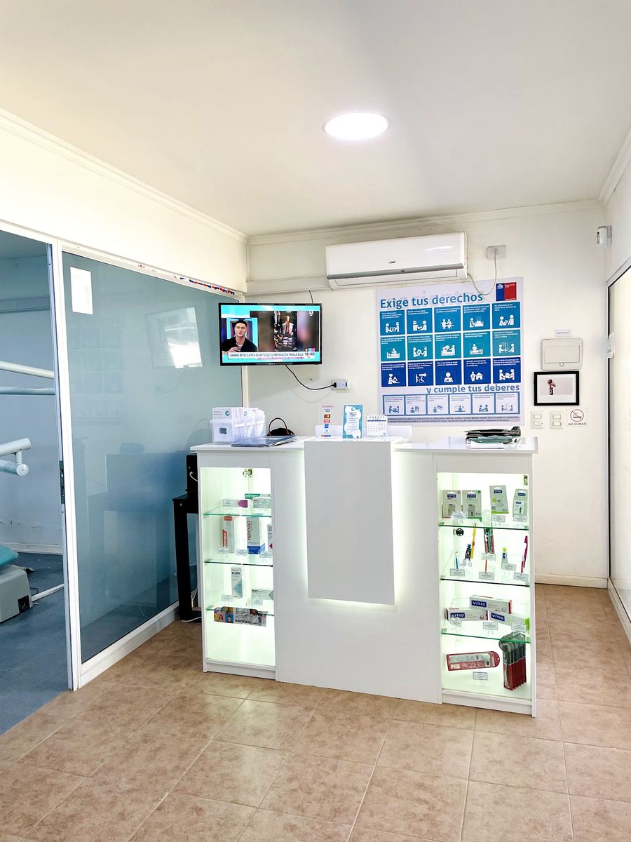 Recepción de la clínica: mesón blanco con vitrinas iluminadas